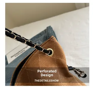 Detail of brown suede quilted bag featuring gold metal eyelets and a classic chain strap