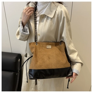 Detail of quilted suede contrast shoulder bag with chain strap and metal lock closure