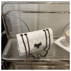 Detail of white quilted handbag with black chain strap and metallic V-shaped clasp