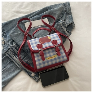 Detail of a mini backpack with red and blue plaid patterns and cute fruit illustrations