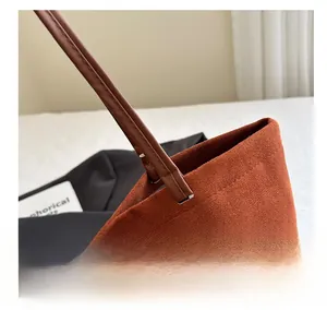 Detail of the brown suede tote bag shoulder strap connection with precise stitching