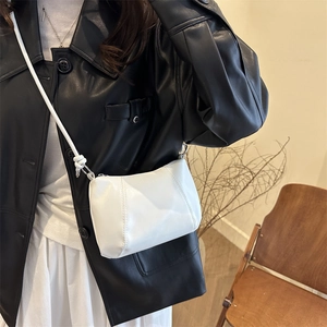 Minimalist white semi-circle crossbody bag with knotted strap detail and metal zipper