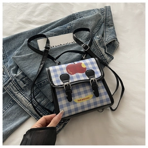 Détail du sac à dos à carreaux bleus avec motif pomme et fermoirs à boucles