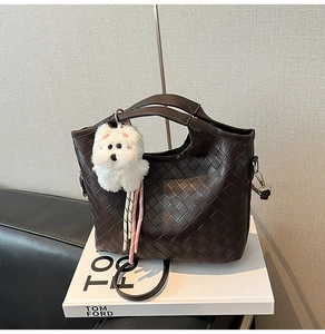 Macro detail of the dark brown woven texture and plush puppy charm on the bucket bag