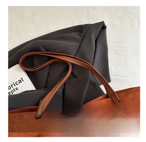 Detail of a brown suede tote bag featuring a premium leather handle and fine stitching detail