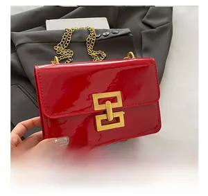 Close-up of red patent leather shoulder bag with gold geometric lock and chain strap
