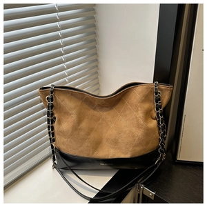 Detailed view of vintage brown suede tote with diamond quilting and black leather trim