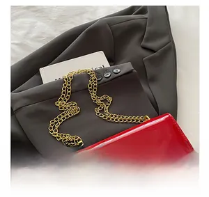 Detailed macro view of glossy red patent leather bag with a bold gold chain and square buckle