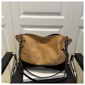 Detail of diamond-quilted brown suede and black leather stitching with gold chain strap