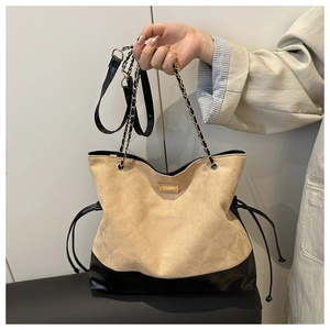 Detail of quilted beige suede tote bag with gold chain strap and drawstring side closure