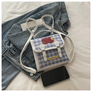 Détail du mini sac à dos à carreaux avec illustration de pomme et texte Not Anxious