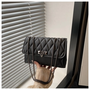 Close-up of black quilted crossbody bag with gold chain strap and metal rivet hardware