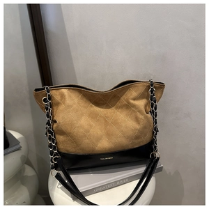 Detail of quilted suede tote bag with chain strap and contrast leather bottom panel