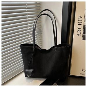 Detail shot of black matte texture tote bag with leather straps and decorative pouch