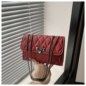 Detail of red quilted PU leather handbag with metal heart-shaped lock and chain strap