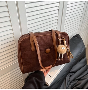 Detail of vintage brown suede hobo bag with top handles and plush monster charm