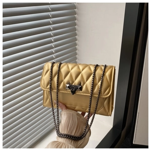 Detail of yellow quilted leather crossbody bag with dark grey metal chain and buckle