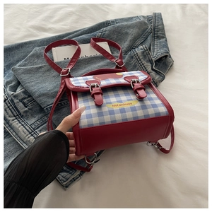 Détail du sac bandoulière à carreaux rouge et bleu avec boucles sur tissu en jean