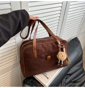 Close-up of vintage brown suede shoulder bag with circular buckle and plush charm detail