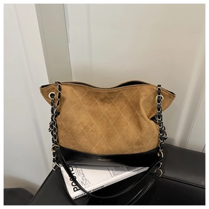 Detail of brown suede and black leather patchwork tote with diamond quilting and chain strap