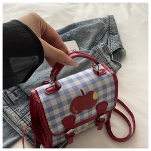 Détail du sac à dos à carreaux bleus avec motif pomme et finitions en cuir rouge