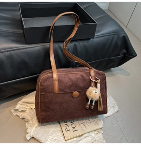 Detail of retro dark brown suede shoulder bag with plush charm and polished buckle accent