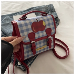 Détail du mini sac à dos à carreaux bleus avec poignées en cuir rouge et motif pomme