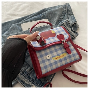 Détail de l'écusson pomme et texte Not Anxious sur le sac en toile à carreaux