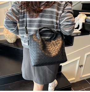 Detailed view of the black woven texture and leather craftsmanship on a luxury tote bag