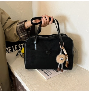 Close-up of black retro tote bag with fuzzy brown charm and stylish circular buckle detail