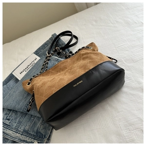 Detail of brown suede and black leather tote bag with quilted diamond pattern and chain