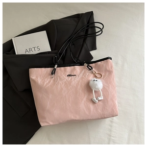 Pink tote bag detail with pleated texture, black straps and cute plush monster charm