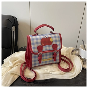 Gros plan d'un mini sac à dos à carreaux avec imprimé pomme et rabat à boucles