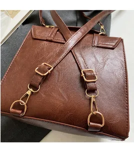 Detail of brown faux leather backpack showing pebbled texture and gold metal hardware