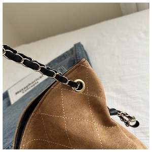 Detail of brown quilted suede texture and metal chain strap on a vintage tote bag