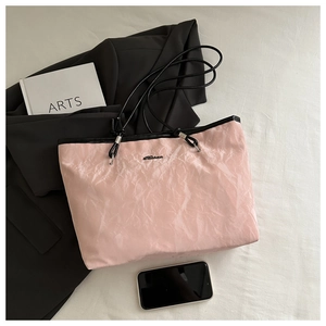 Detail of pink tote bag with pearlescent pleated texture and black cord handles