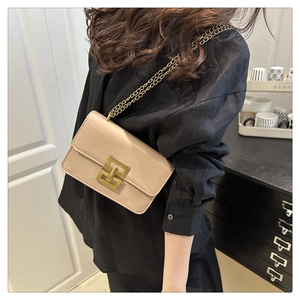 Detail of beige patent leather crossbody bag with gold chain strap and square metal buckle