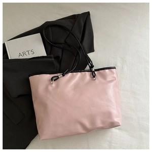 Detail of pink tote bag with black handles placed on a blazer for business look