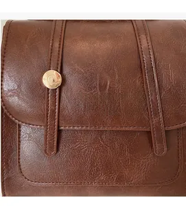 Close-up of brown textured PU leather surface with gold rivets and brand lettering