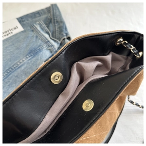 Close-up of quilted suede tote showing gold magnetic closures and metal chain straps