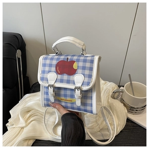 Détail du mini sac à dos à carreaux bleus avec motif pomme et bretelles blanches