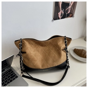 Detail of diamond-quilted brown suede tote bag with chain strap and contrast black base