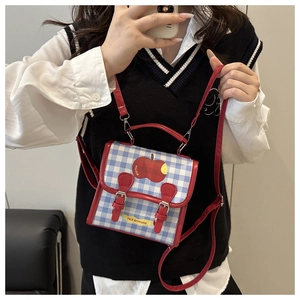 Détail du sac à carreaux bleus avec imprimé pomme et boucles rouges élégantes