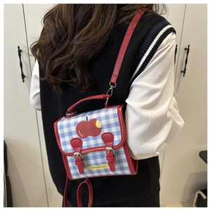 Détail du sac à bandoulière vichy bleu et blanc avec imprimé pomme rouge sur un modèle