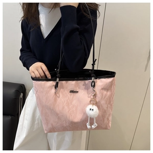 Detail of pink tote bag featuring wrinkled fabric texture and a plush charm
