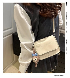 Détail du sac bandoulière blanc crème avec motifs ours gaufrés et breloque peluche