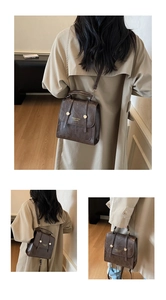 Detail of vintage dark brown PU leather mini backpack with gold buckle and top handle
