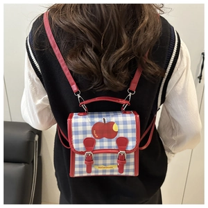 Détail d'un petit sac à dos à carreaux bleu et blanc avec motif pomme rouge