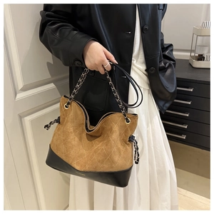 Detail of brown suede quilted tote with black leather trim and chain strap on a model