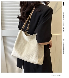 Detail view of cream white tote bag with crocodile texture and gold hardware rings